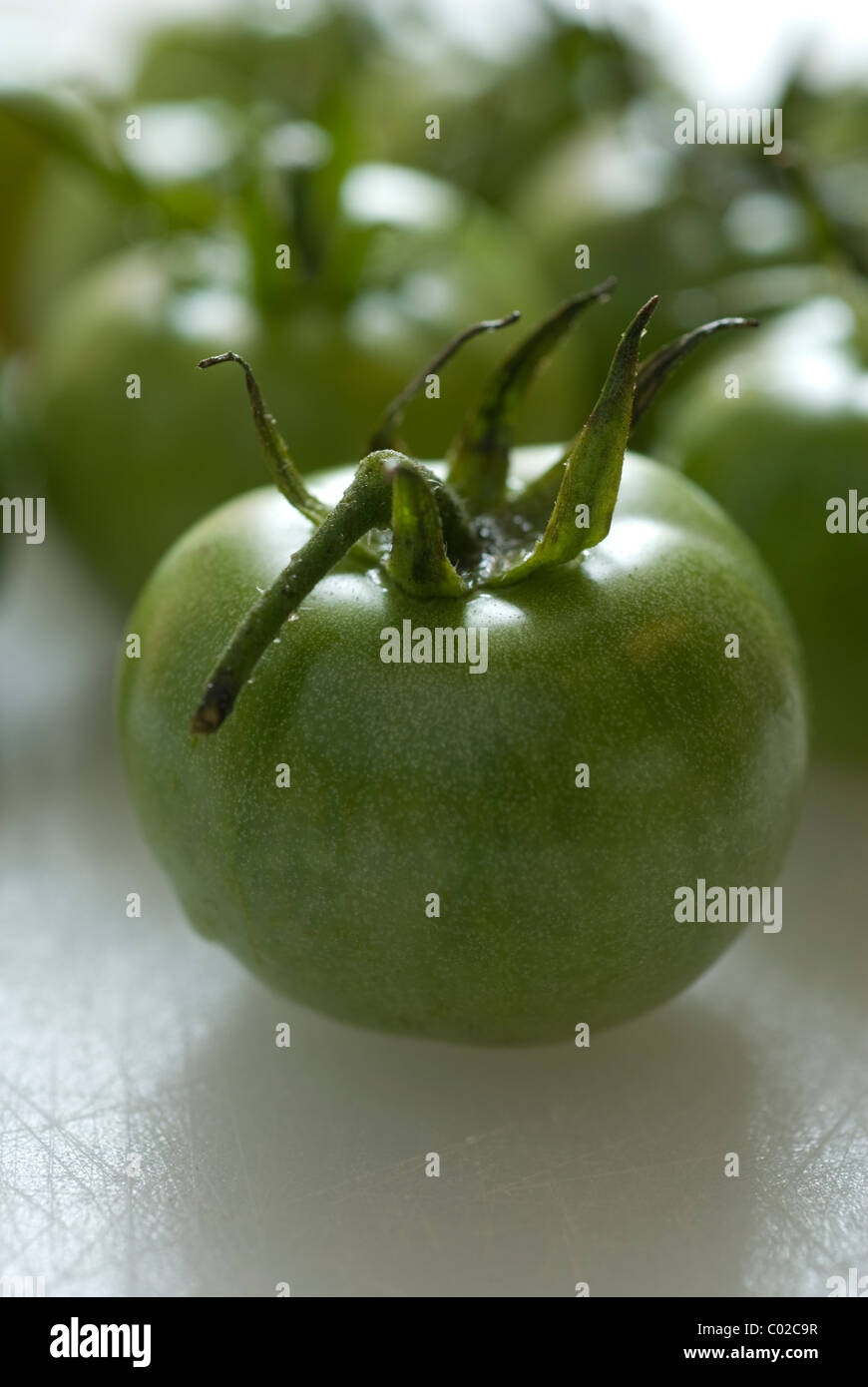 Tutto il pomodoro verde su bianco un tagliere. Foto Stock