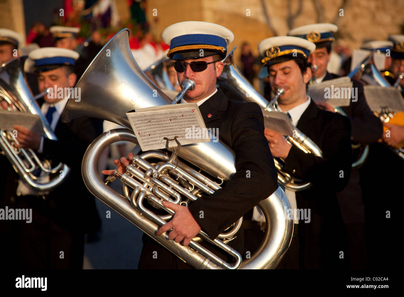 I membri di una banda di ottoni in abiti scuri, riproduci musica durante la street parade che commemora il Venerdì Santo che si terrà a Malta. Foto Stock