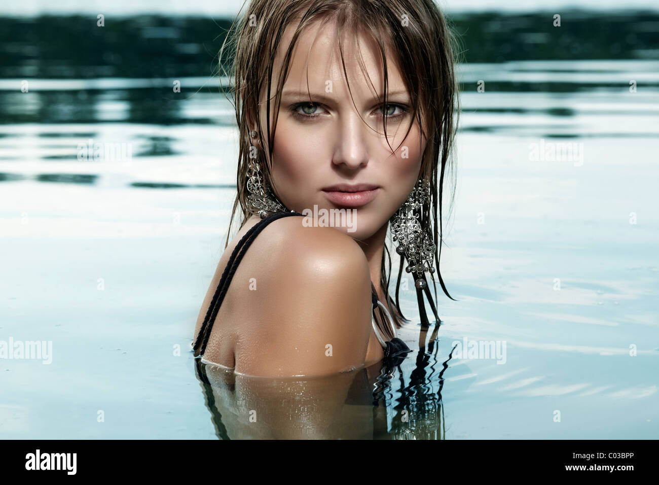 Giovane donna in nero di un costume da bagno e con capelli bagnati, balneazione in un lago Foto Stock