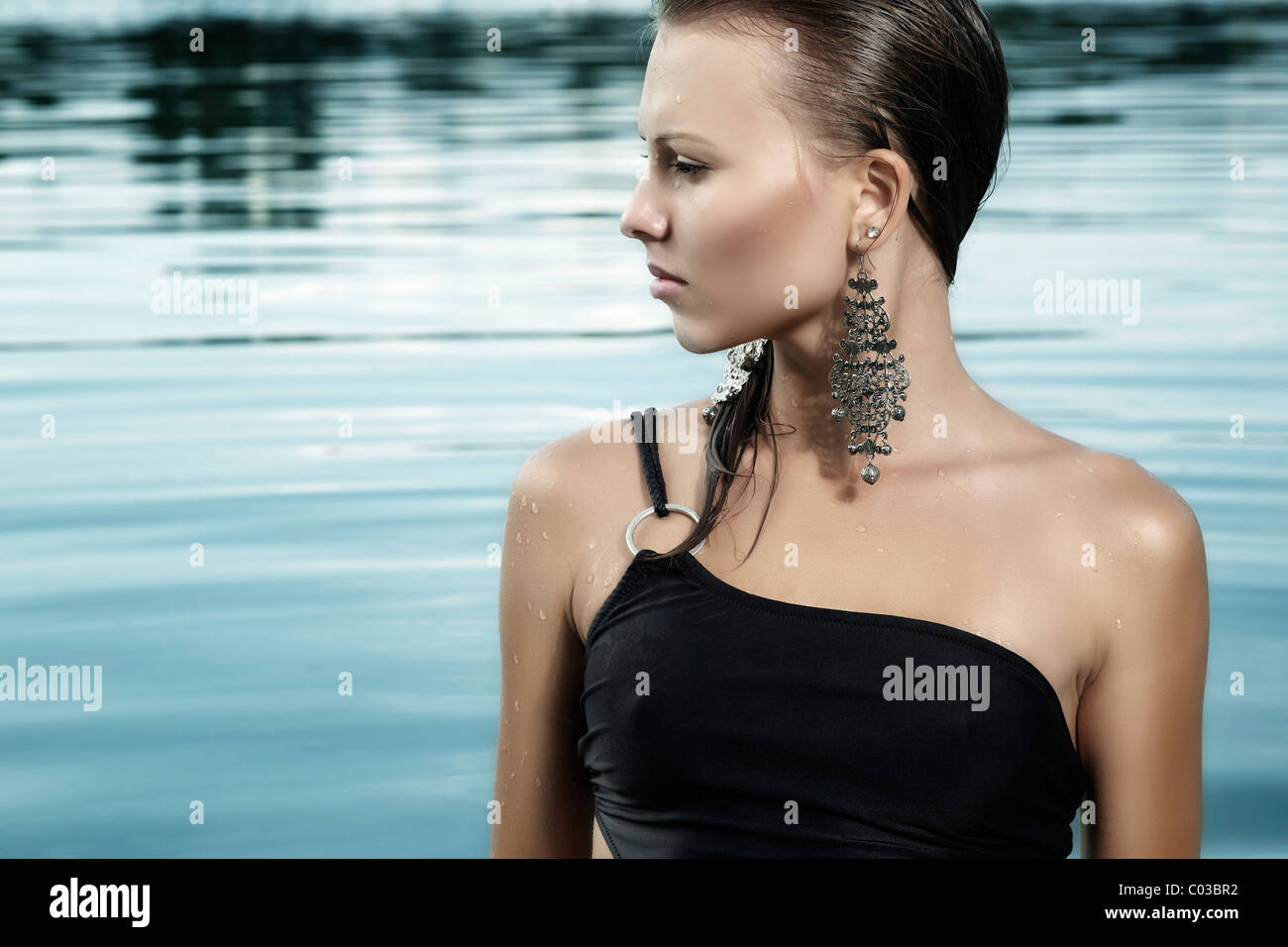 Giovane donna in nero di un costume da bagno e con capelli bagnati, balneazione in un lago Foto Stock
