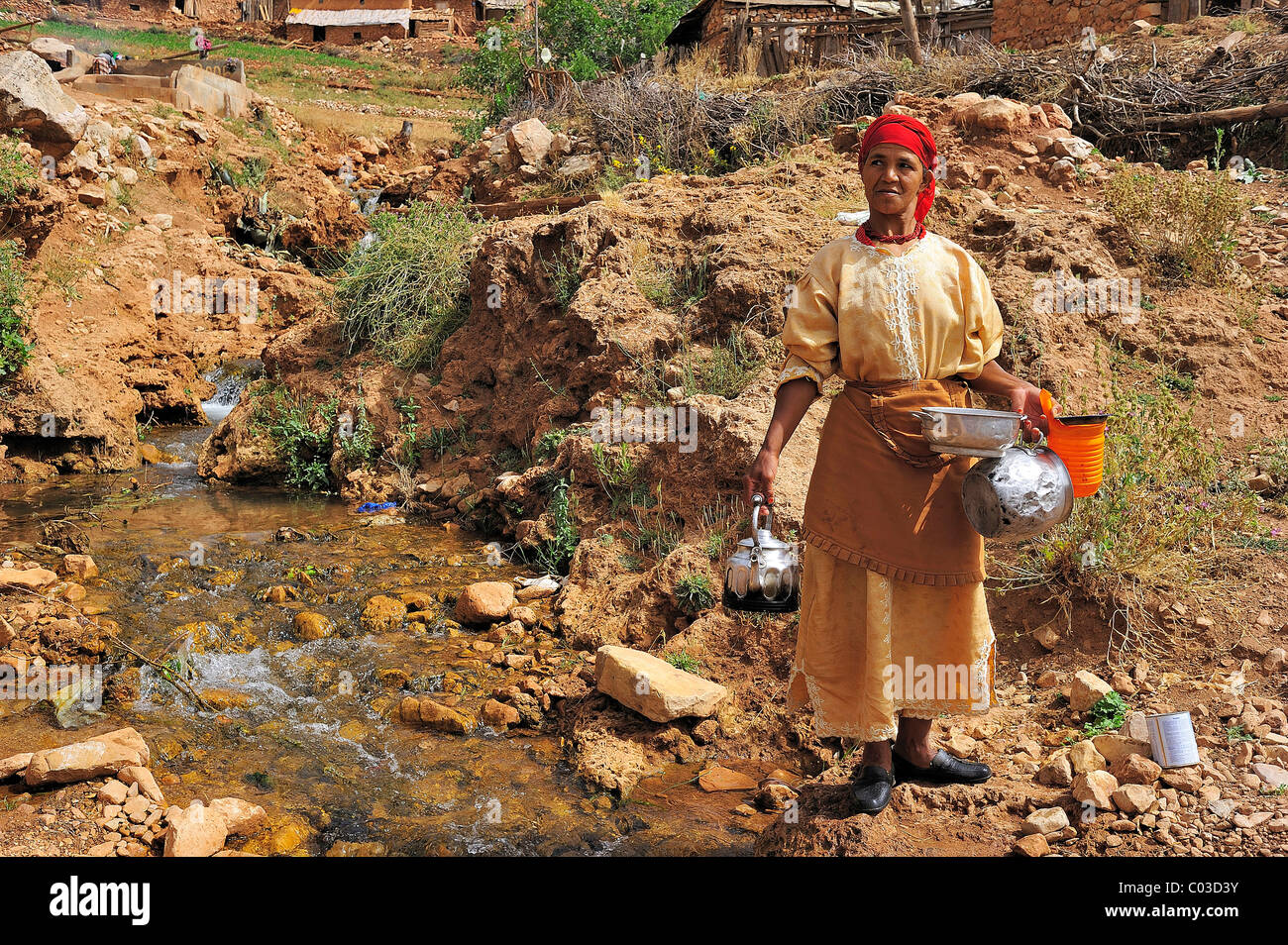 Anziana donna berbera lavando i suoi piatti in un torrente, Medio Atlante in Marocco Foto Stock