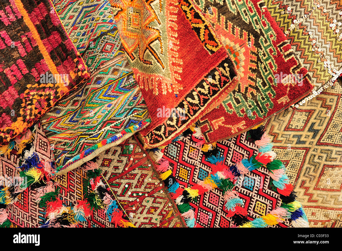 Colorato cuscino in tessuto copre con ornamenti tradizionali dei Berberi e arabi venduti da un concessionario nel souk, Bazaar, Marocco Foto Stock