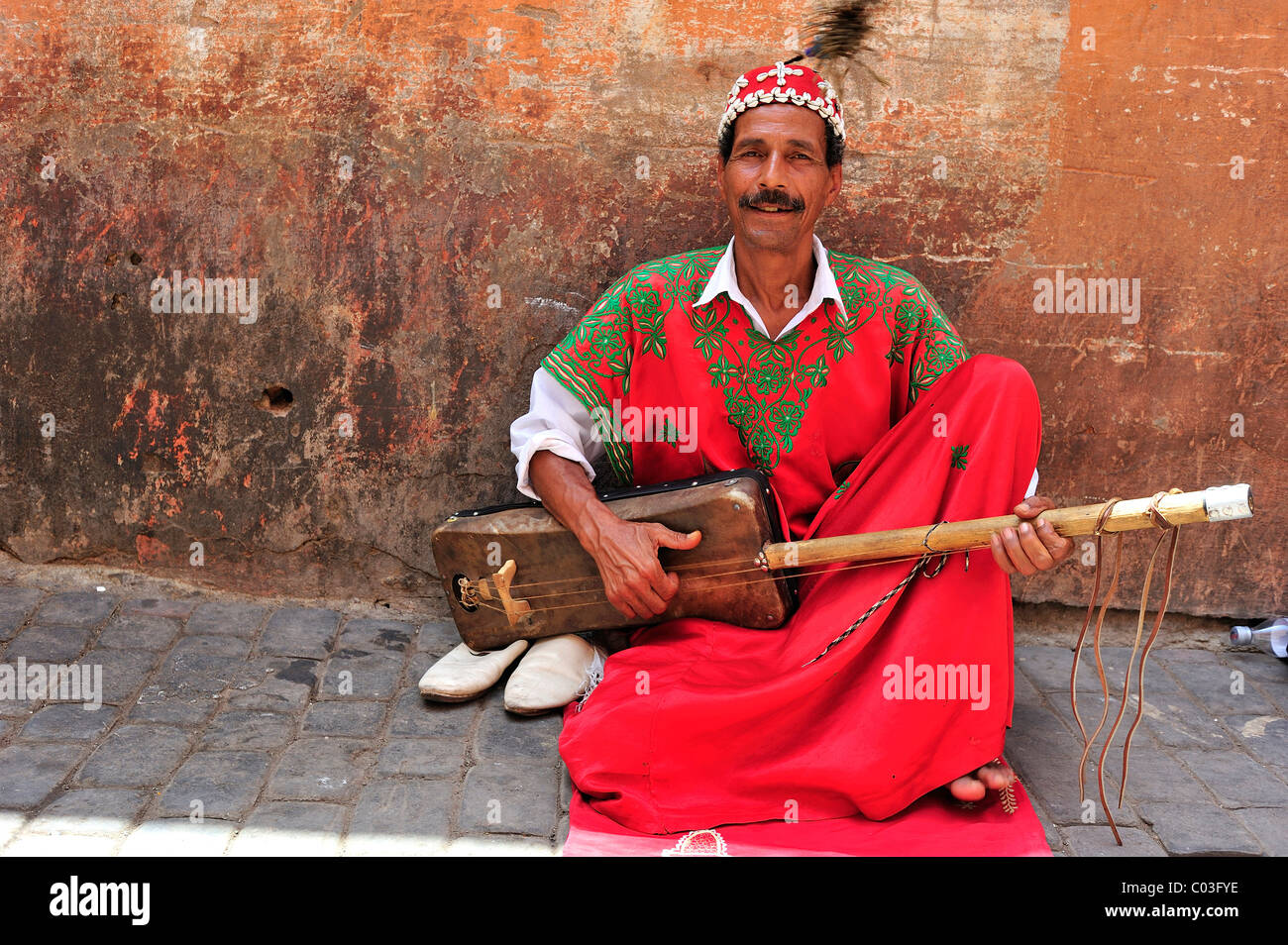 Musicista di strada indossando abiti tradizionali a giocare il suo strumento musicale, Marrakech, Marocco, Africa Foto Stock