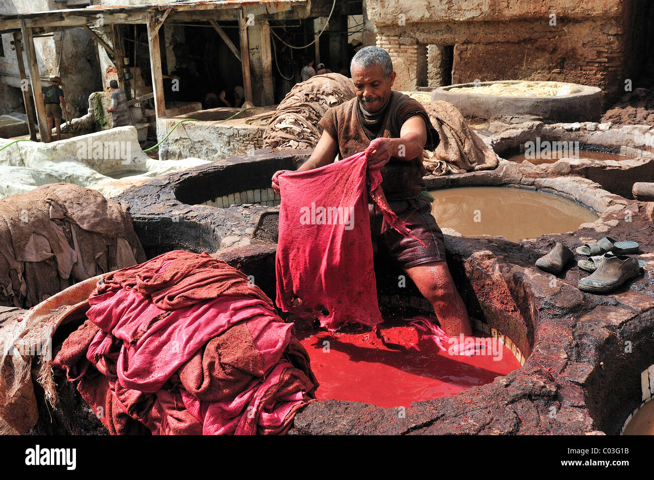 Lavoratore in piedi in una vasca di vernice rossa per tingere il cuoio in una conceria, i conciatori e tintori trimestre, Fez, in Marocco, Africa Africa Foto Stock