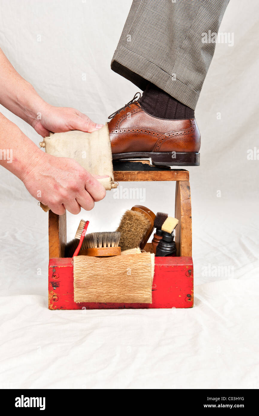 Un uomo prende le sue scarpe lucide da un lavoratore utilizzando un vintage lustrascarpe box Foto Stock