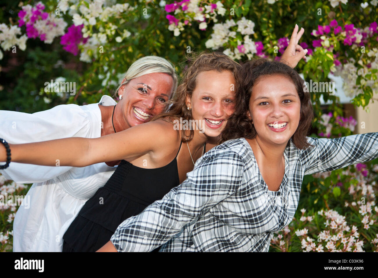 Ritratto di una madre con due tredici anni ragazze nella parte anteriore dei fiori Foto Stock