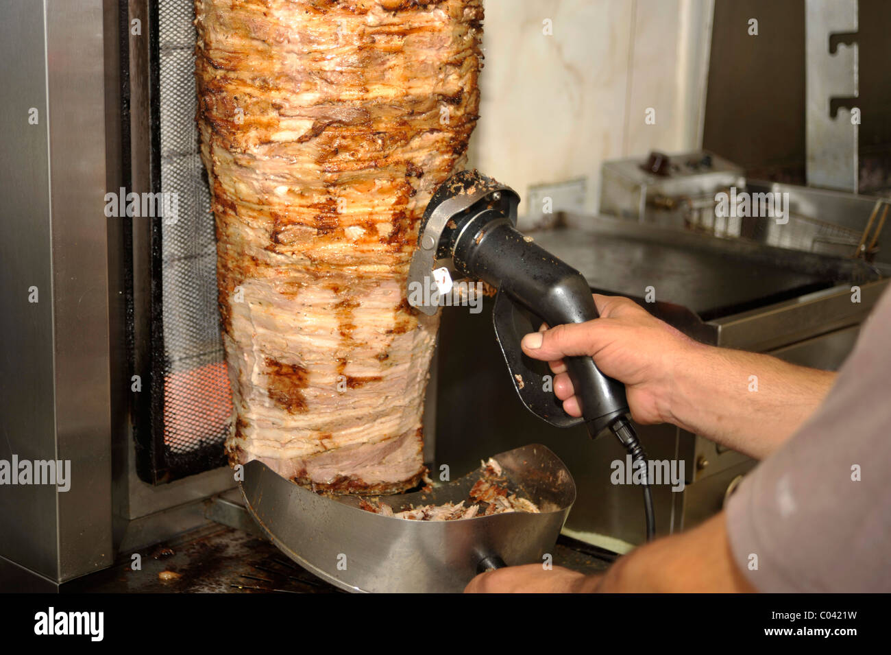 Gyros greco sputare su un grill. Un uomo il taglio di carne fuori. Foto Stock