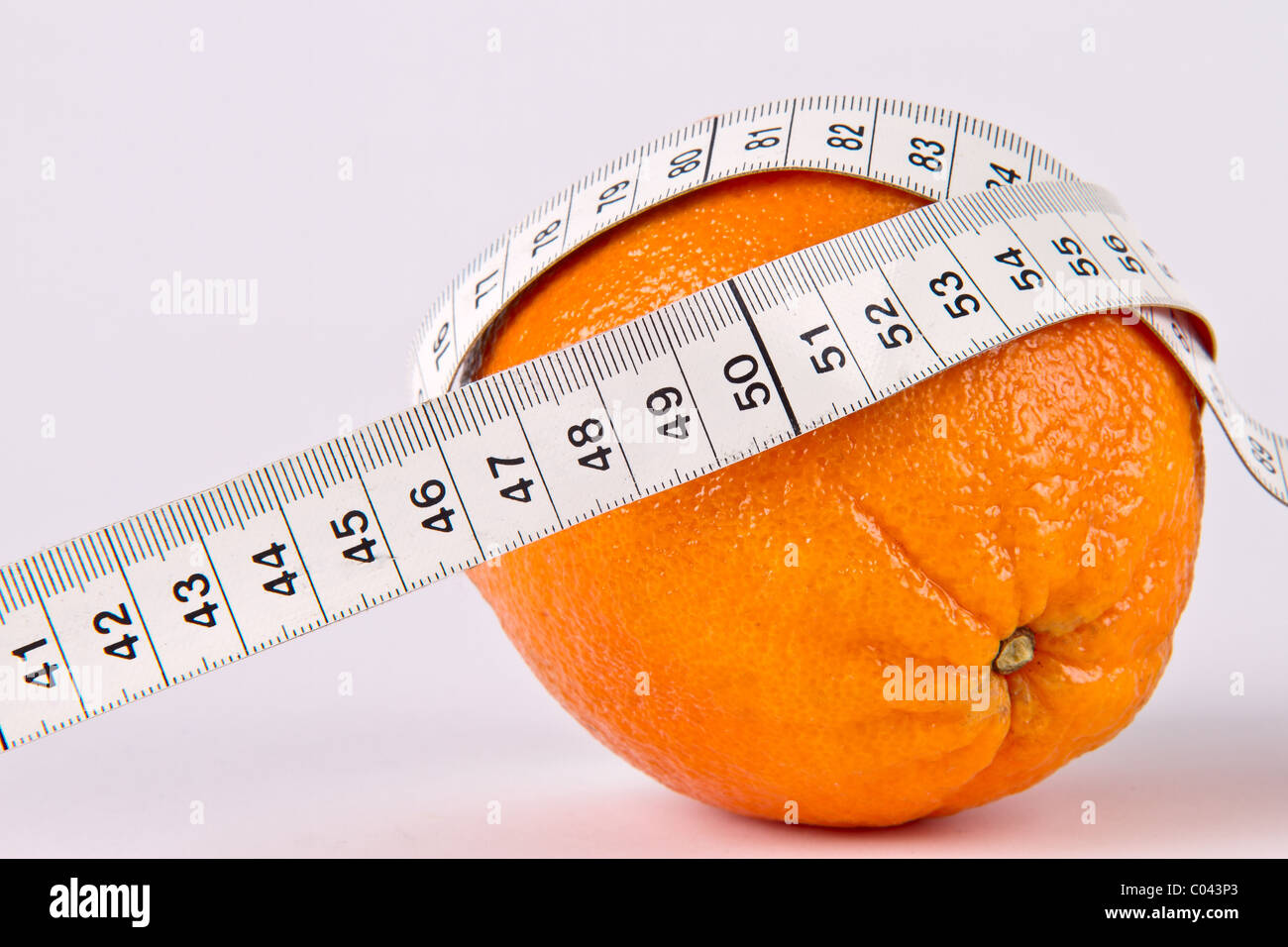 Frutta di arancia con nastro di misurazione su sfondo bianco Foto Stock