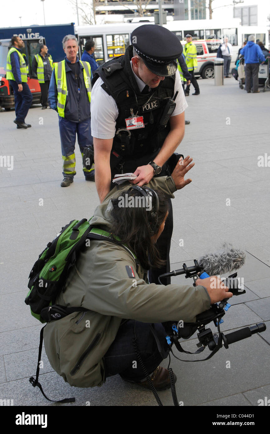 Parlare di polizia affrontare un videografo prendere copertura IVA protester all'aeroporto di Heathrow di Londra Foto Stock