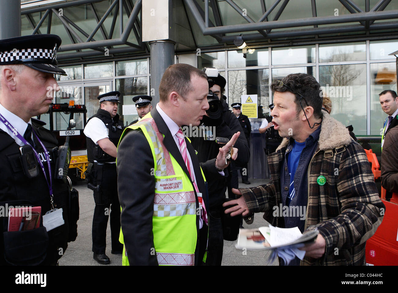 Airport Duty Maanger parla di prendere IVA protester all'aeroporto di Heathrow di Londra Foto Stock