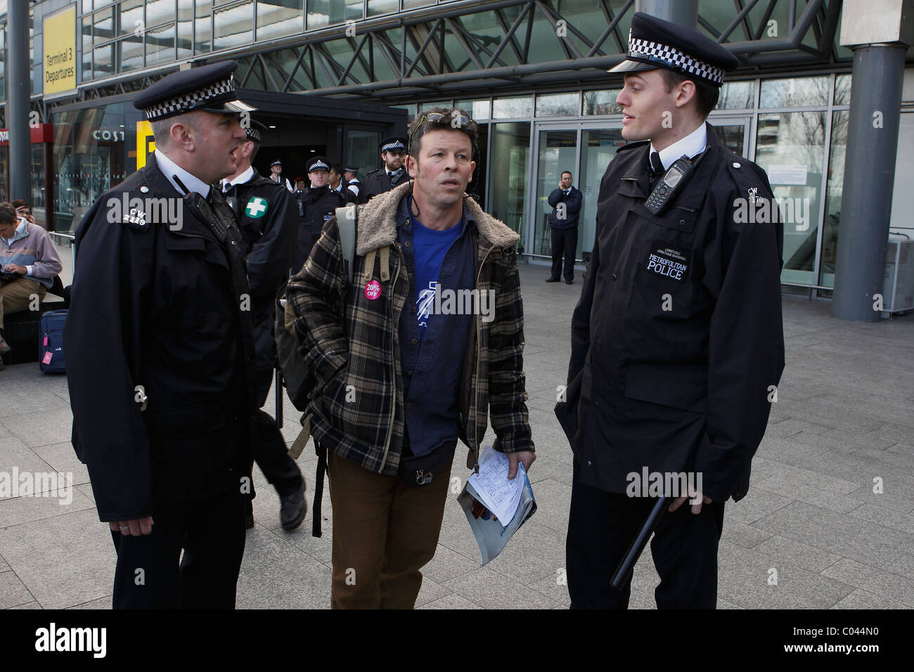 Parlare di polizia a prendere IVA protester all'aeroporto di Heathrow di Londra Foto Stock