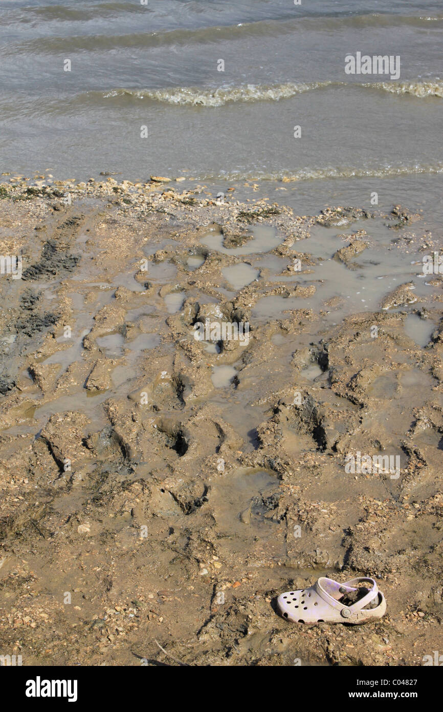 Un Croc calzatura bloccata nel fango al mare Foto Stock