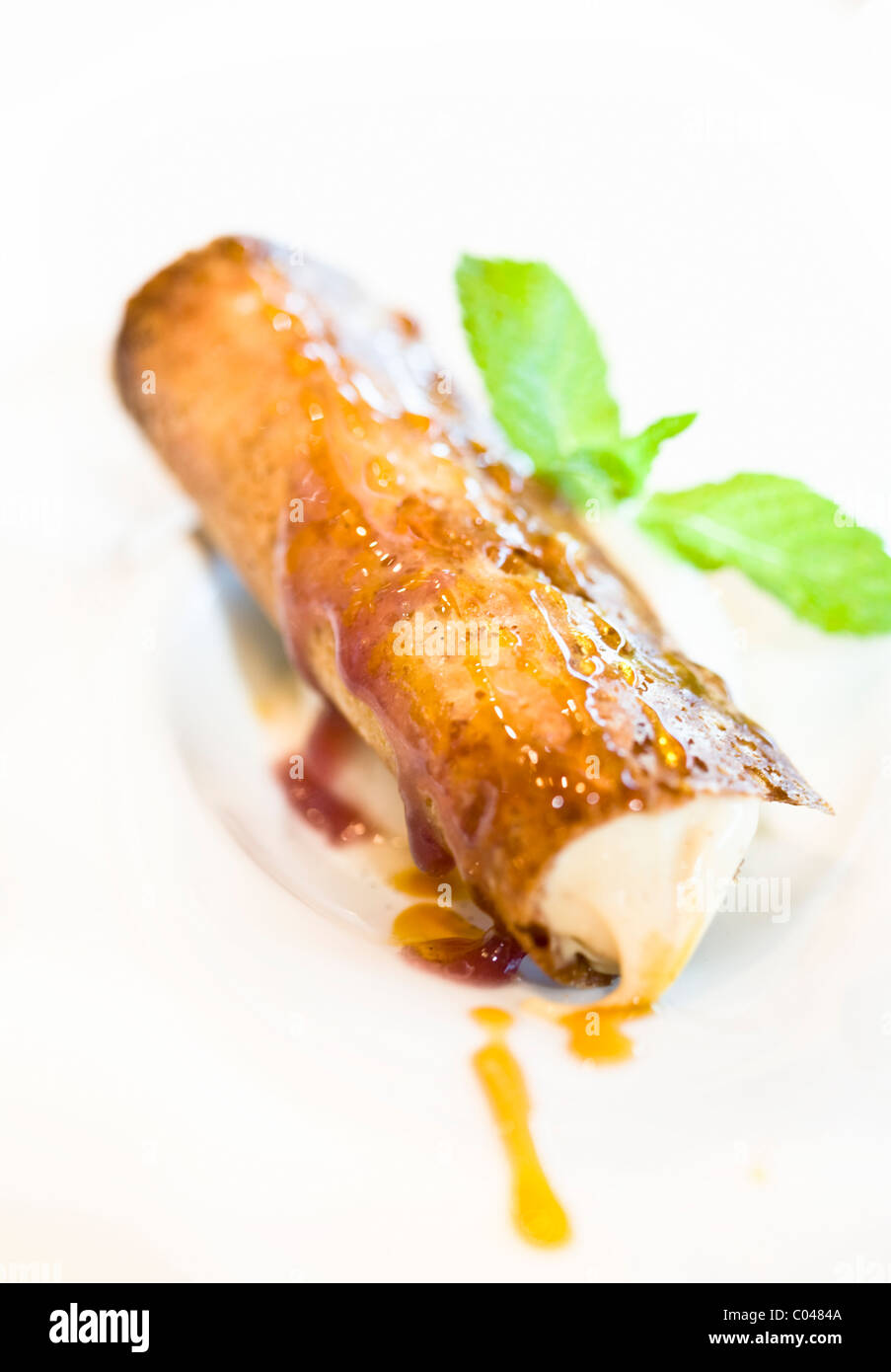 Il Brandy snap riempito con gelato alla vaniglia guarnito con menta fresca Foto Stock