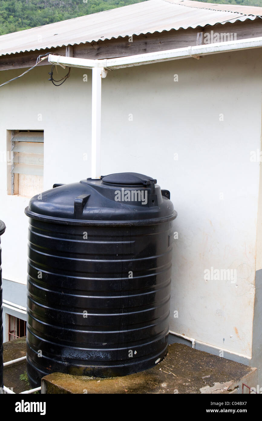 Vecchia cisterna per l'acqua raccoglie acqua piovana runoff attraverso il tetto grondaia. Foto Stock