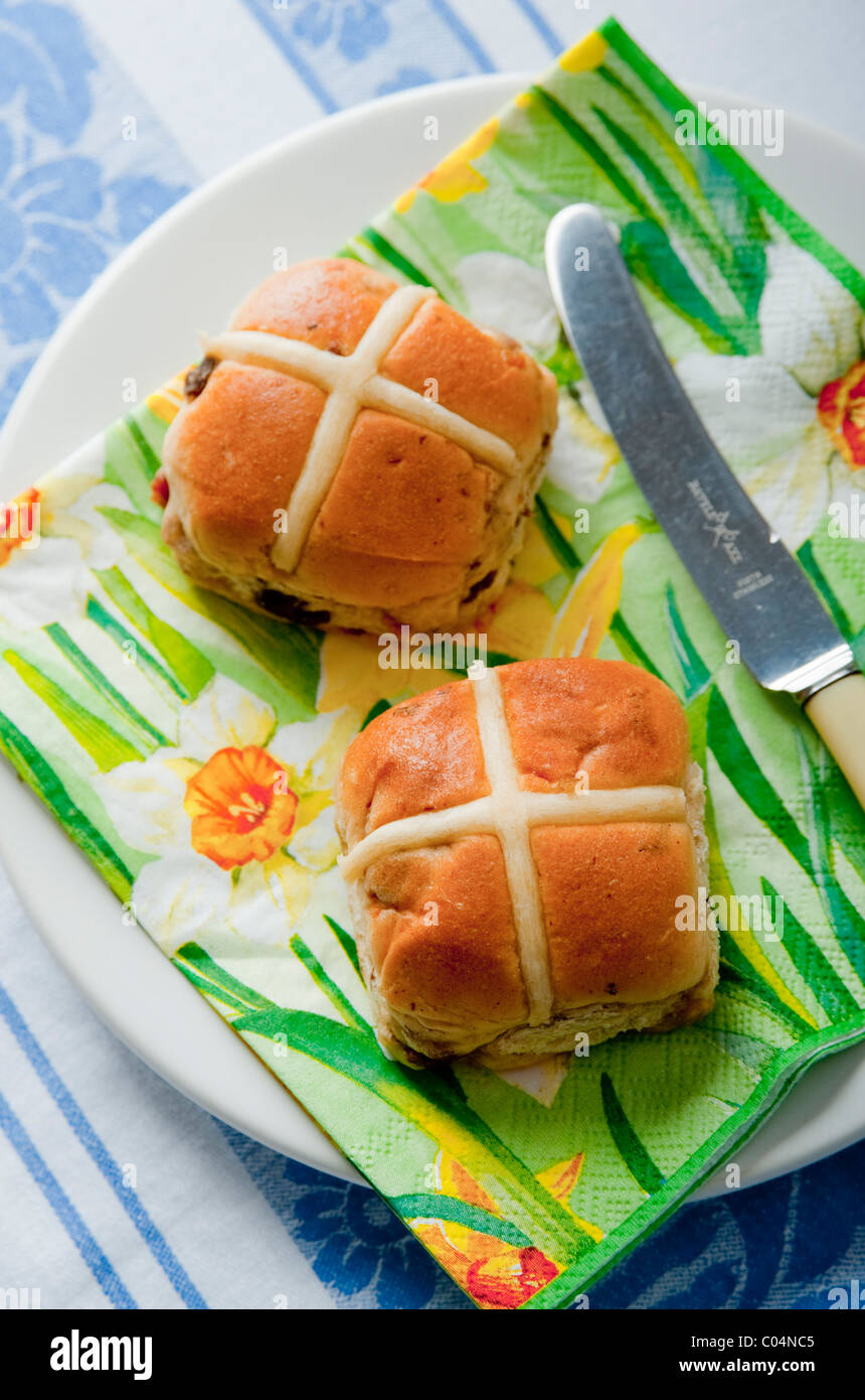 Pasqua a caldo imburrato ciambelle trasversale sul lato bianco con piastra daffodil tovagliolo sulla tovaglia Foto Stock