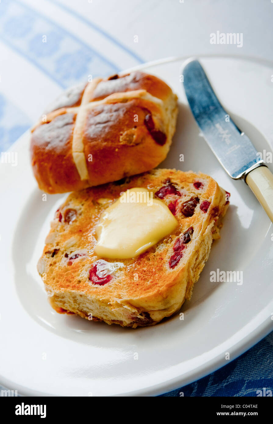 Pasqua a caldo imburrato ciambelle trasversale sul lato bianco con piastra daffodil tovagliolo sulla tovaglia Foto Stock