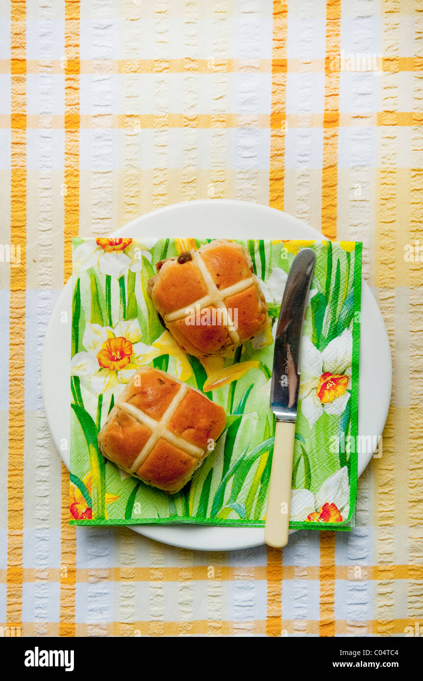 Pasqua a caldo imburrato ciambelle trasversale sul lato bianco con piastra daffodil tovagliolo sulla tovaglia Foto Stock