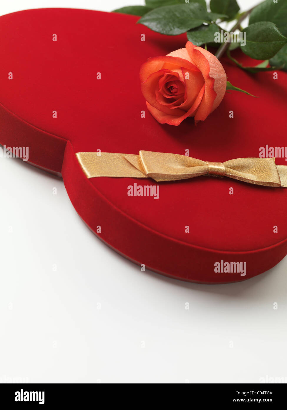 Cuore rosso a forma di scatola regalo e una rosa rosa su sfondo bianco Foto Stock