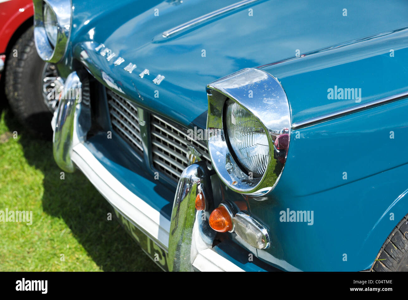 Il paraurti e la griglia e i proiettori su un classico trionfo Herald in blu con luccicanti chrome opera in corrispondenza di un veicolo vintage visualizza Foto Stock