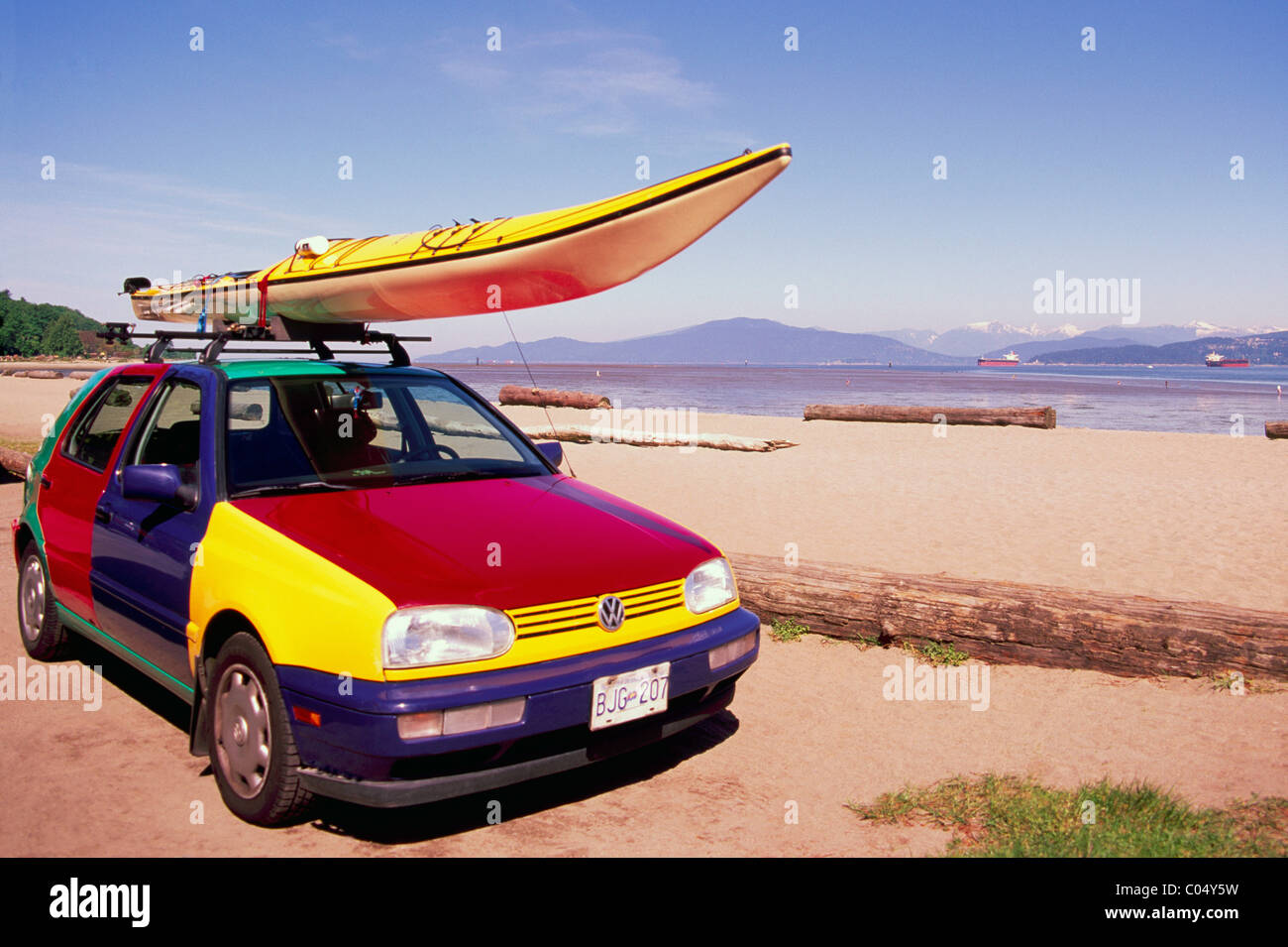 Kayak giallo montato su variopinti tetto Volkswagen, VW automobile parcheggiata sulla spiaggia, le banche spagnole, Vancouver, British Columbia, Canada Foto Stock