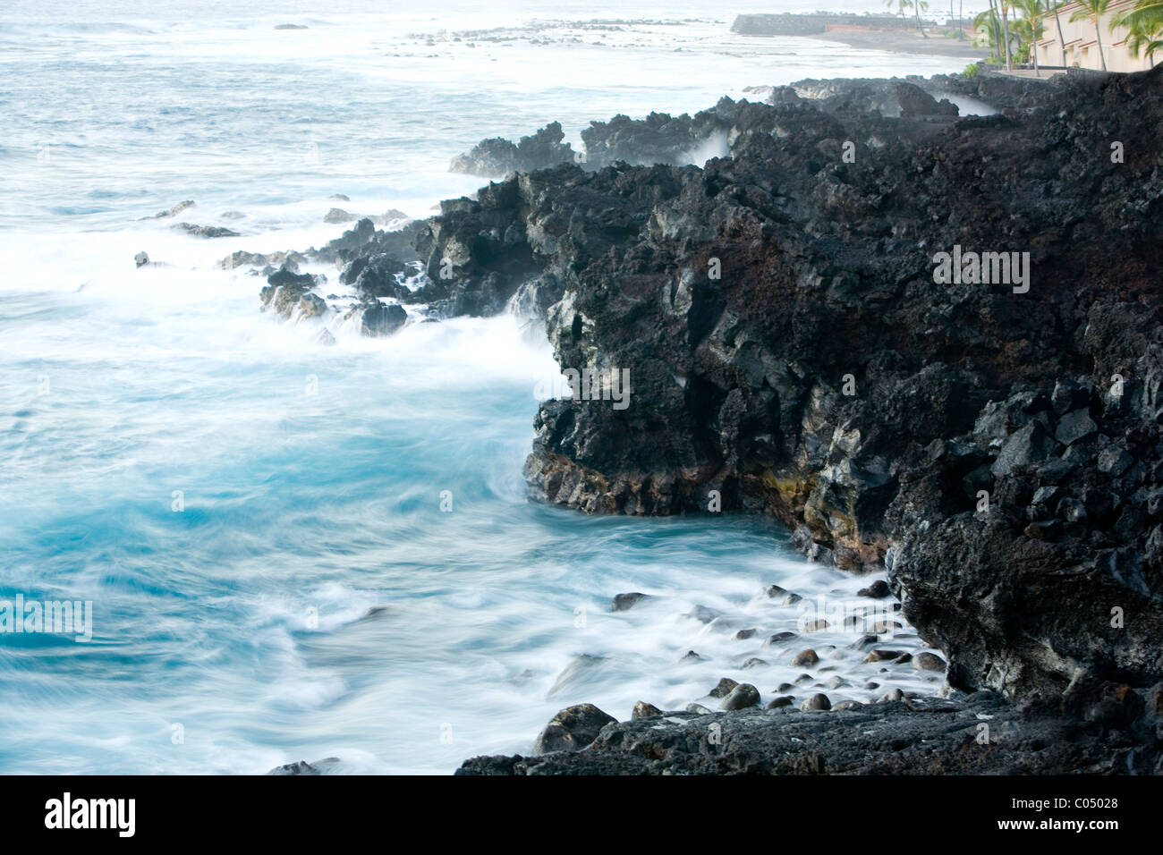 Il tempo di esposizione di surf di tornitura contro rocce laviche in Kailua Kona Foto Stock