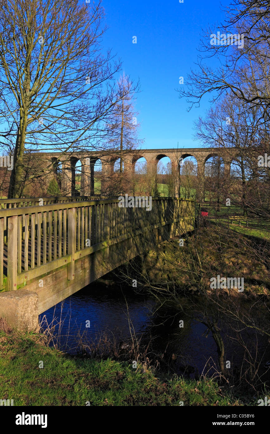 Passerella in legno sopra il fiume Don conduce ai prati di Acqua Park e il viadotto ferroviario, Penistone, South Yorkshire, Inghilterra, Regno Unito. Foto Stock