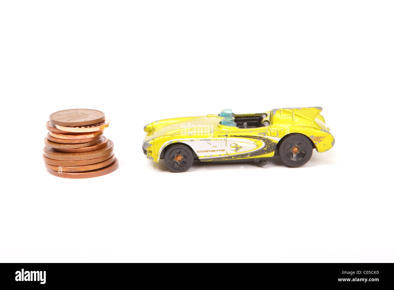 Giocattolo Antico Corvette auto con pila di penny spiccioli monete il costo dell'automobilismo Foto Stock