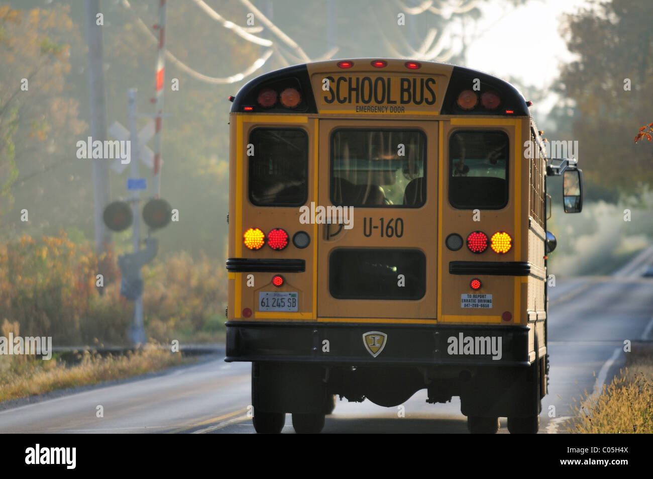 Wayne, Illinois, Stati Uniti d'America. Una scuola i segnali del bus come esso rallenta per fare una sosta obbligatoria presso i binari della ferrovia sulla strada di un paese. Foto Stock