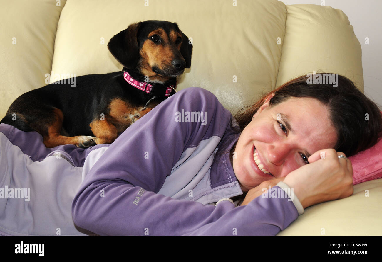 Un cane avvolto a ricciolo addormentato su una donna addormentata Foto Stock