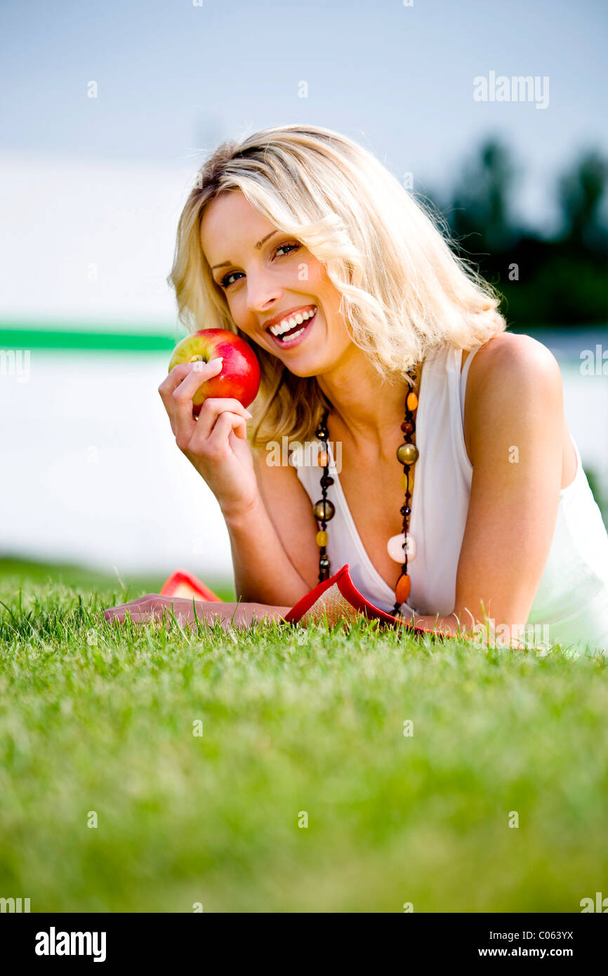 Giovane donna con Apple in un prato Foto Stock