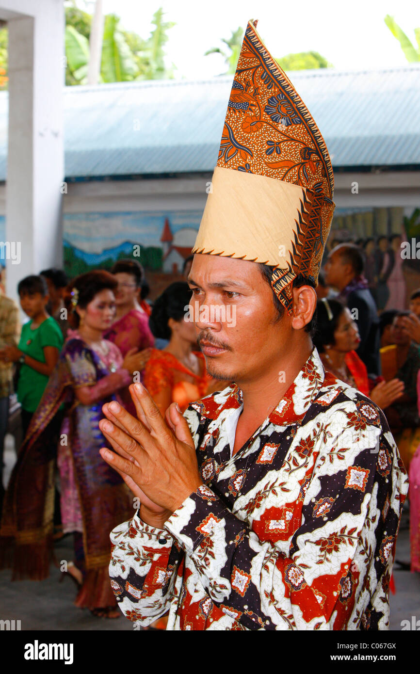 Uomo con le sue mani tenute insieme, gli ospiti a una cerimonia di nozze, Siantar, Batak regione, Sumatra, Indonesia, Asia Foto Stock