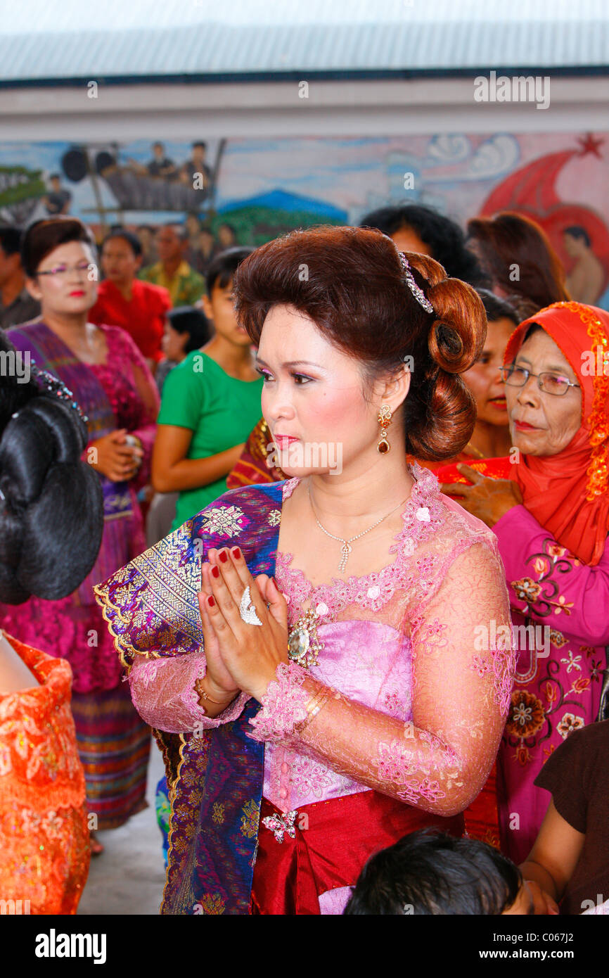 Donna con le sue mani tenute insieme, gli ospiti a una cerimonia di nozze, Siantar, Batak regione, Sumatra, Indonesia, Asia Foto Stock
