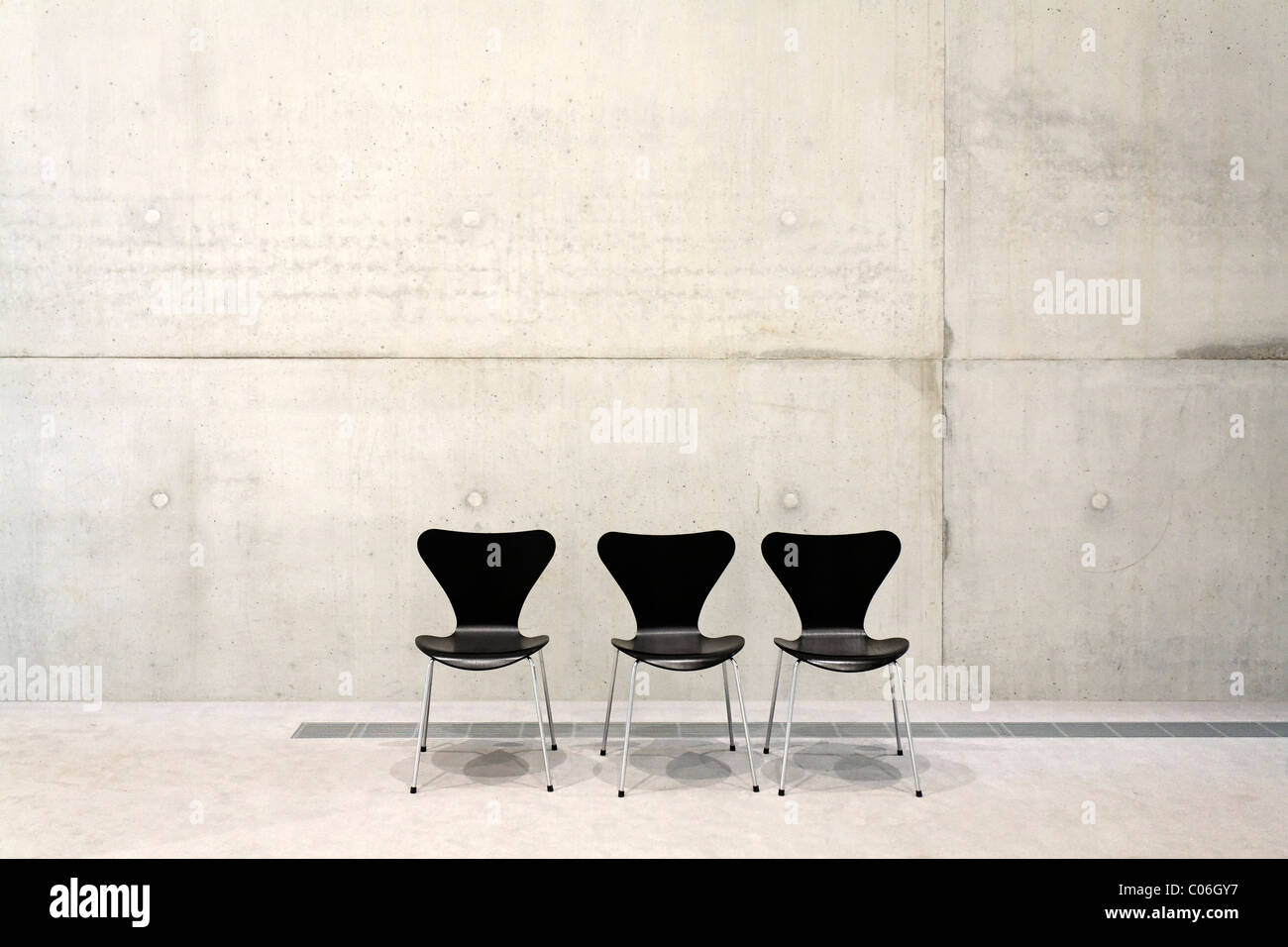 Visitatori tre sedie di fronte a un muro di cemento, SANAA building, Sito Patrimonio Mondiale dell'UNESCO Zeche Zollverein di Essen Foto Stock