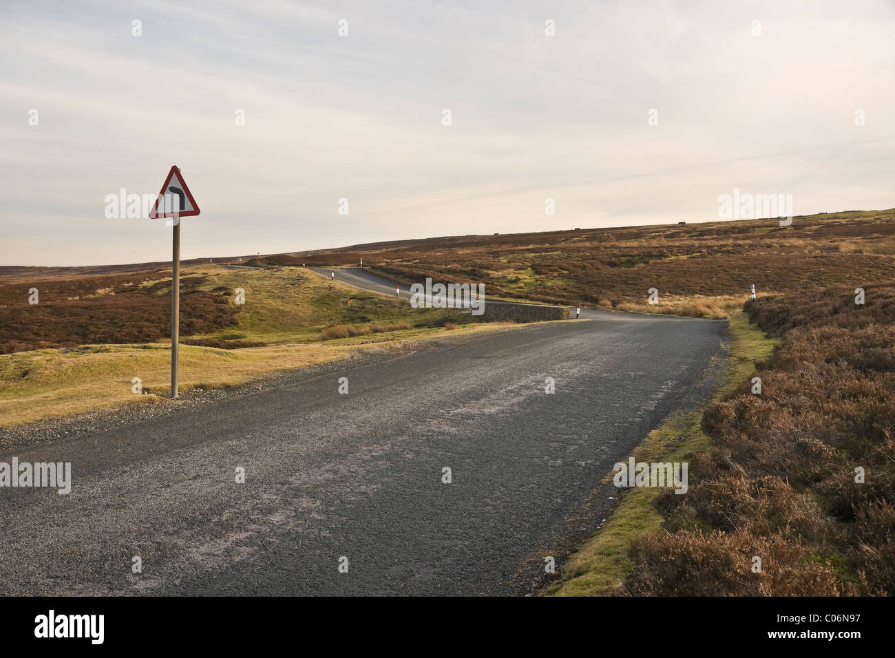 Piegare segno su una stretta strada di campagna che attraversa un brughiera nel North Yorkshire. Sopra Swaledale Ellerton (Grinton a Leyburn Road) Foto Stock
