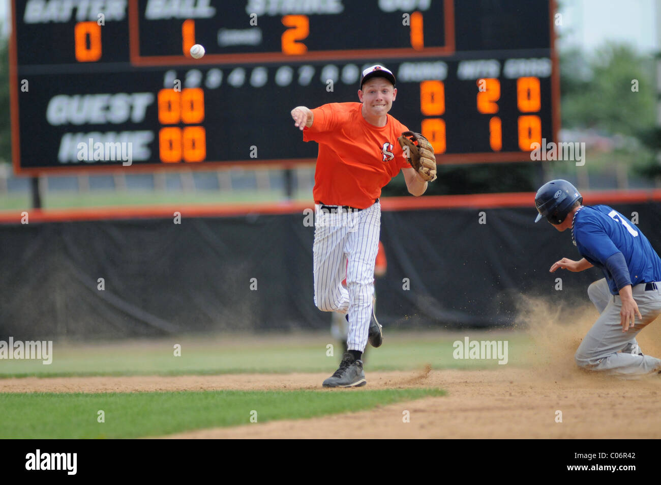 Alta scuola di baseball gioco giocatore lancia baseball dopo la guida di base. Stati Uniti d'America. Foto Stock