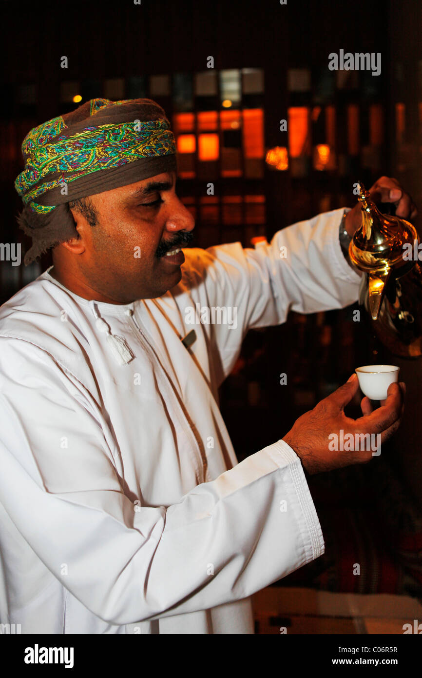 Un uomo Omani serve caffè arabo da un piatto conosciuto come Dallah in Muscat Oman. Foto Stock