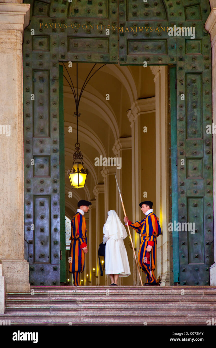 Nun passeggiate attraverso ingresso del Vaticano tra le protezioni dell'esercito svizzero nel tradizionale di uniformi, Roma, lazio, Italy Foto Stock