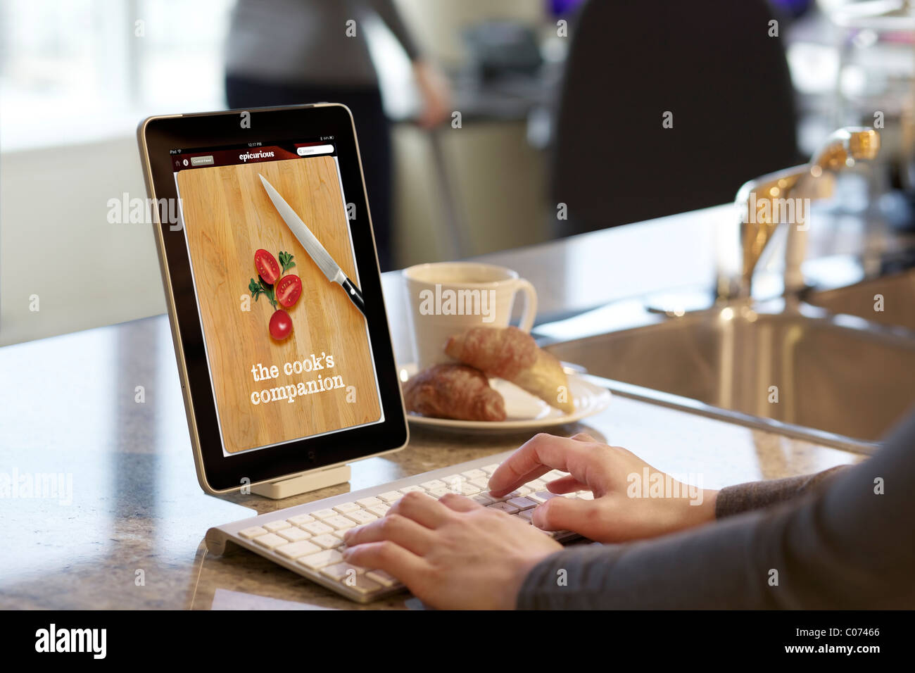 Donna navigazione ricetta di cucina con iPad Epicurious app di cottura Foto Stock