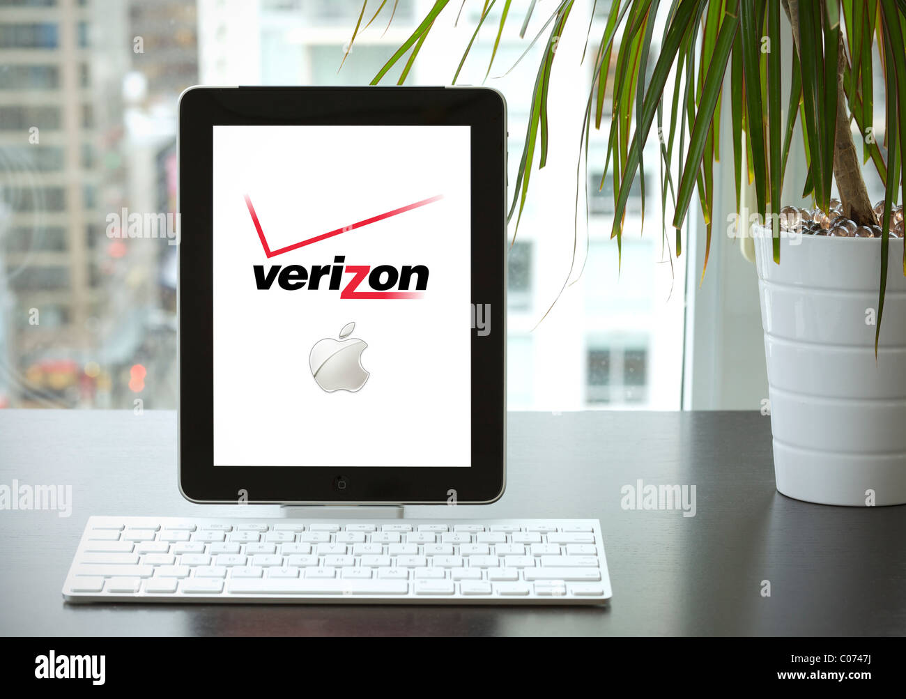IPad essendo utilizzato in un ufficio con tastiera wireless bluetooth mostra Verizon e logo Apple sullo schermo Foto Stock