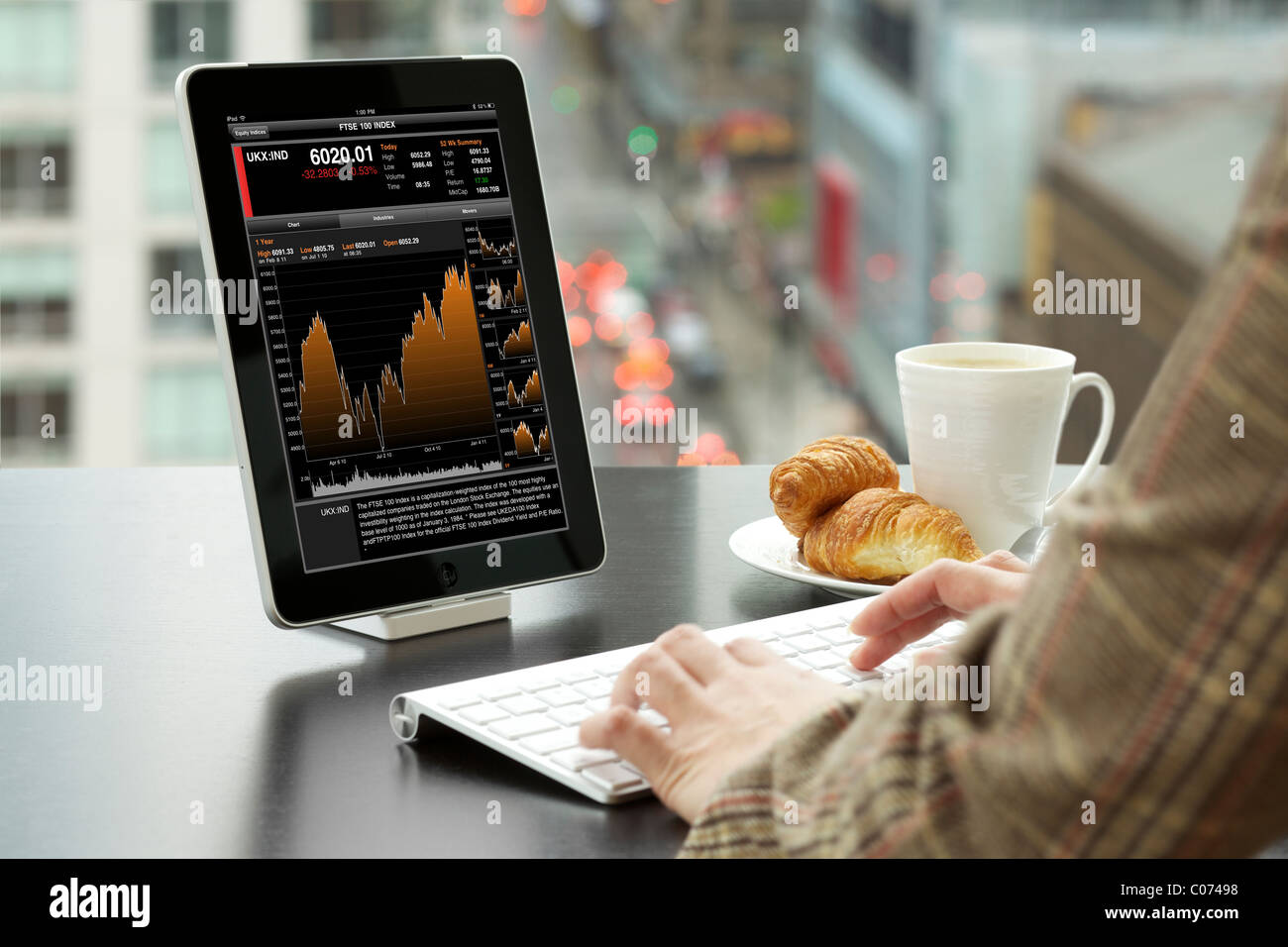 Business donna analizzando FTSE 100 informazioni finanziarie con Bloomberg app iPad presso un ufficio Foto Stock