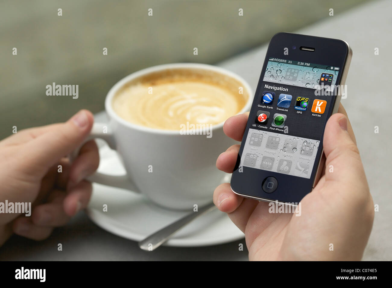 L'uomo godendo il suo cappuccino mentre la mano che regge un iPhone 4 che mostra il nuovo iPhone (retina display/300 dpi) nella schermata dell'applicazione Foto Stock