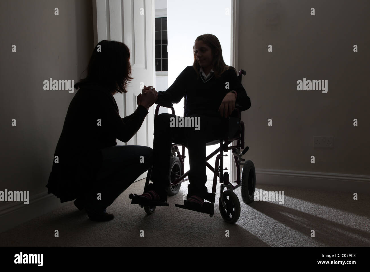 Donna consolante di una giovane donna seduta su una sedia a rotelle, tenendo le mani. Foto Stock