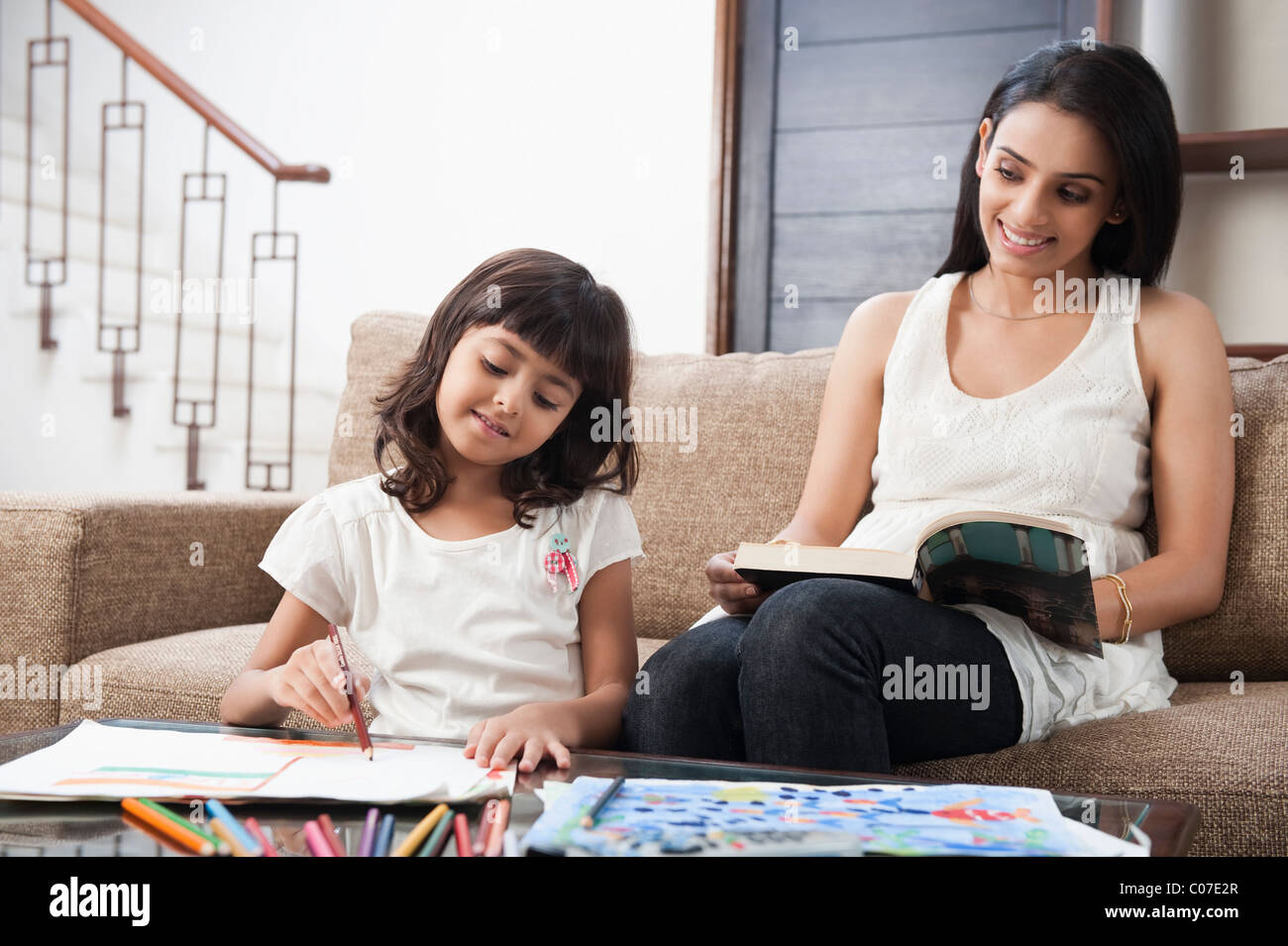 Donna che guarda la sua figlia di disegno Foto Stock