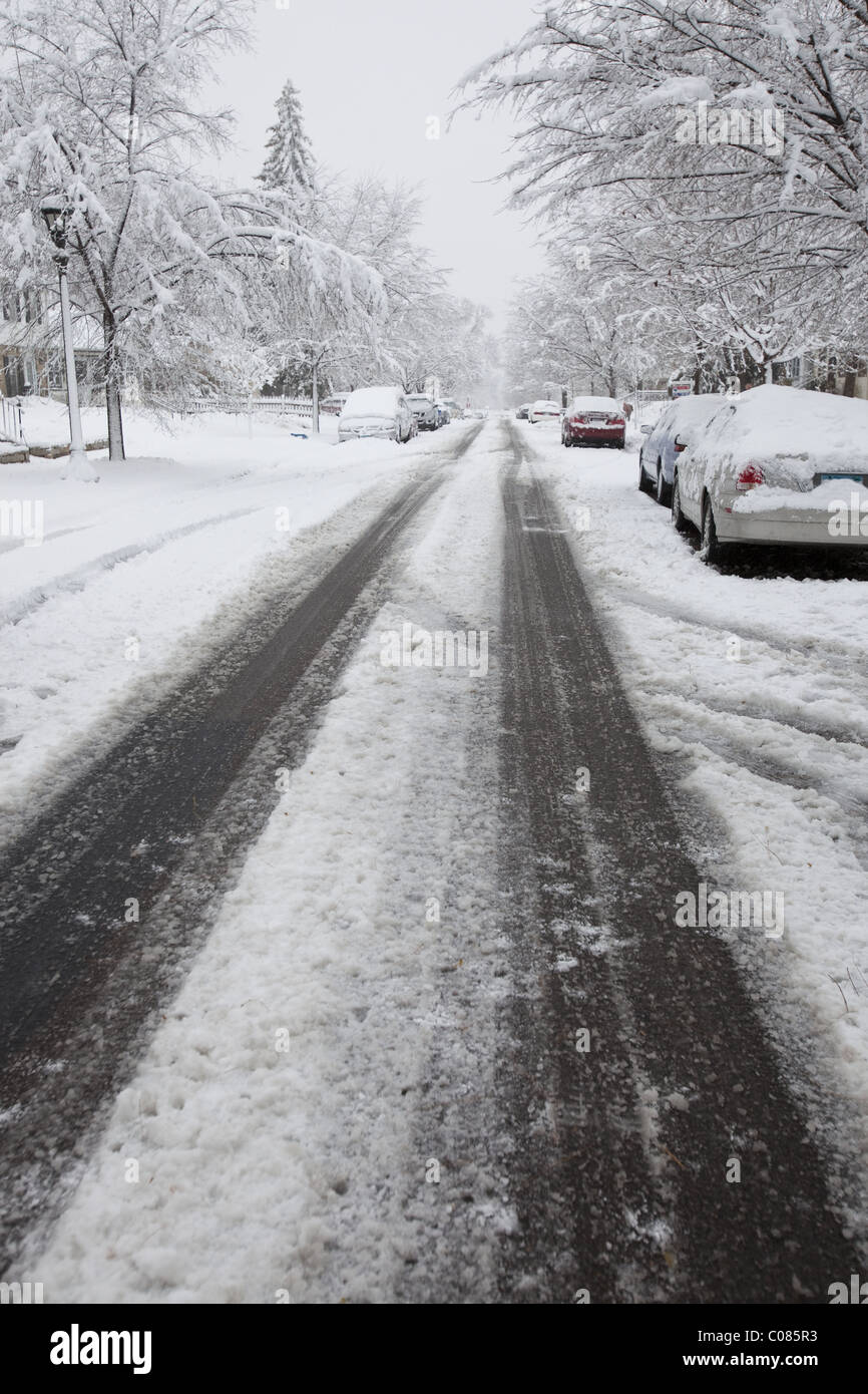 Tracce di pneumatici a sinistra da vetture in una zona residenziale dopo un inizio di tempesta di neve Foto Stock