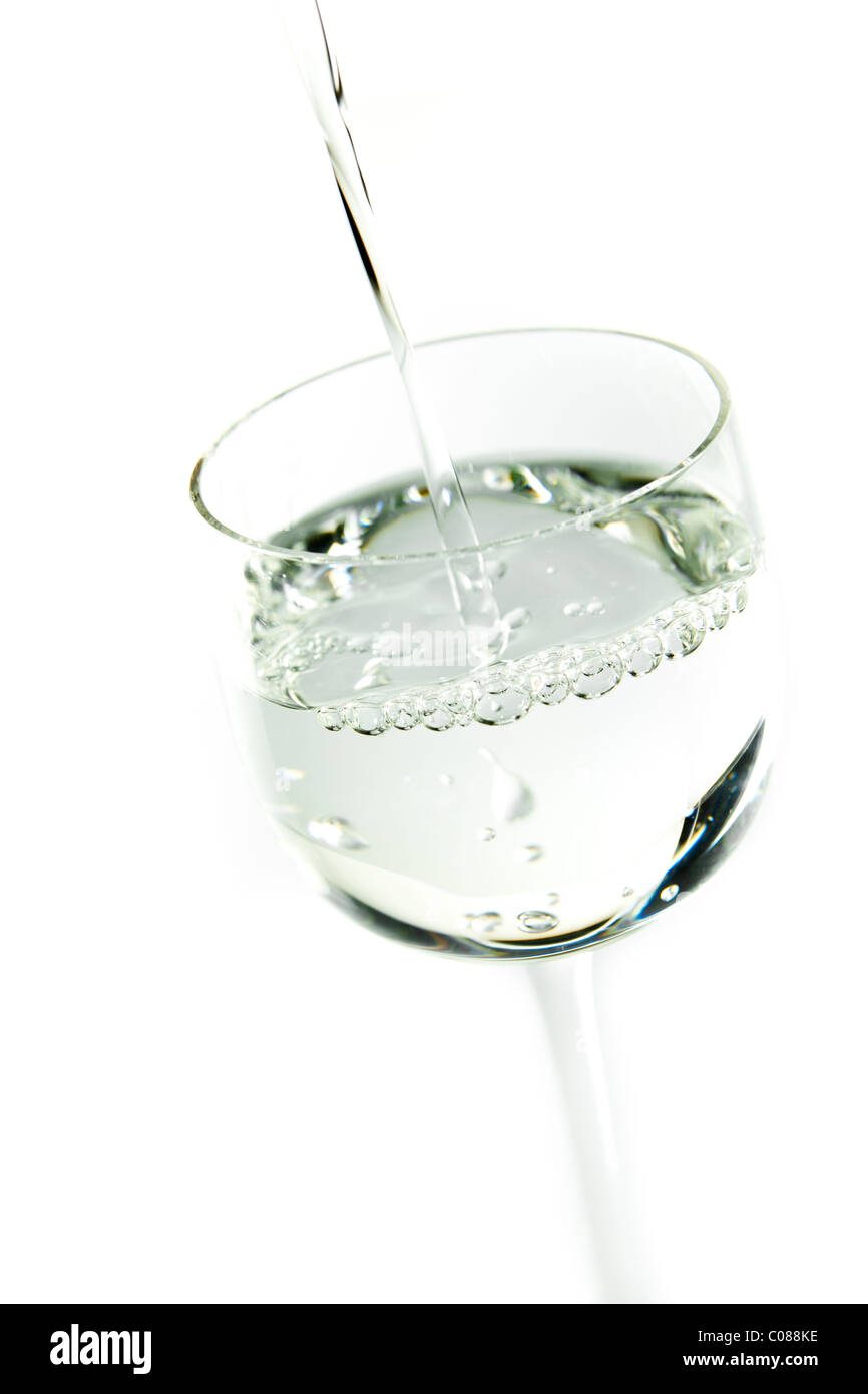 Un bicchiere di sambuca che viene versato su uno sfondo bianco. Foto Stock