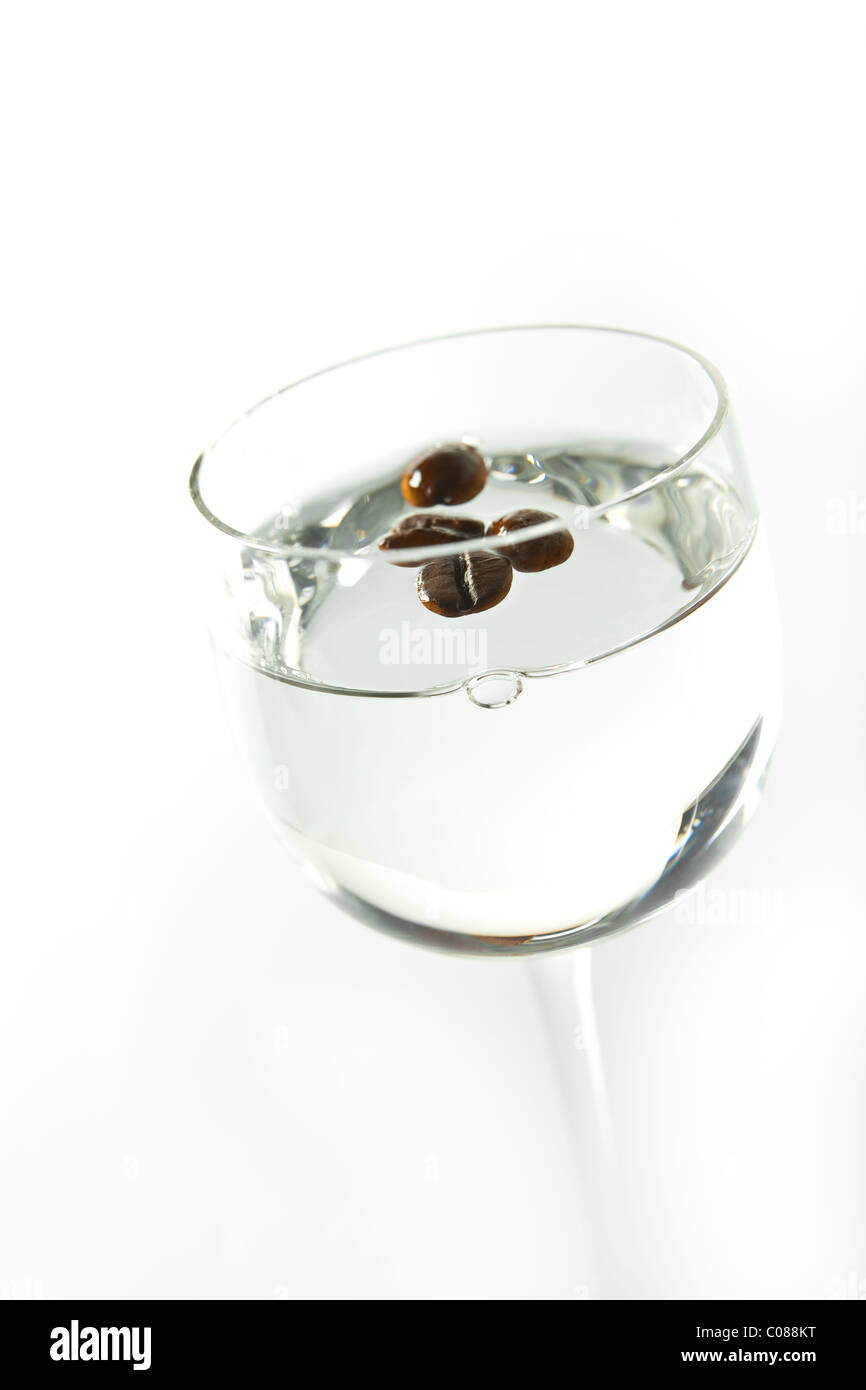 Un bicchiere di sambuca con intero Fagioli coffée uno sfondo bianco. Foto Stock