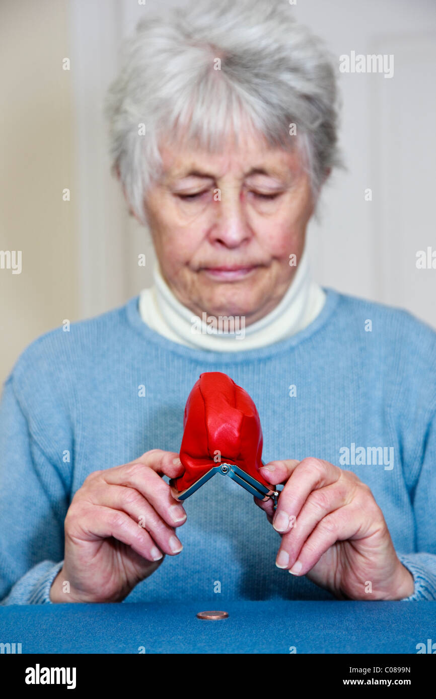 Senior povera donna anziana pensionata su piccole pensioni statali con nessun denaro e un espressione triste lo svuotamento di un centesimo moneta al di fuori di un portamonete. Regno Unito Gran Bretagna Foto Stock
