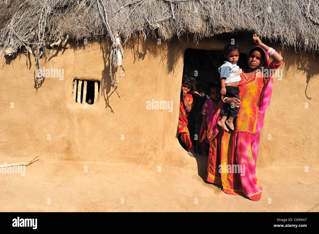 La donna in un sari con un bimbo piccolo all'ingresso a casa sua, deserto di Thar, Rajasthan, Nord India, India, Asia Foto Stock