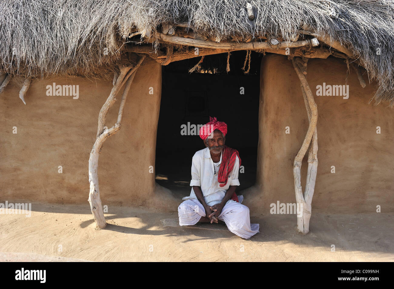 Uomo con turbante in corrispondenza della porta frontale a casa sua, deserto di Thar, Rajasthan, Nord India, India, Asia Foto Stock