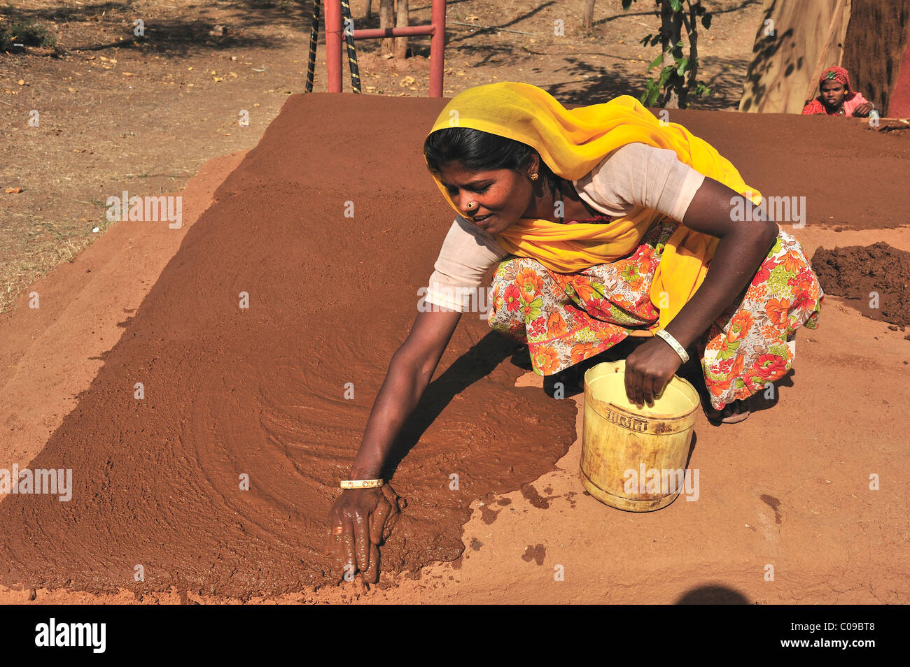 Una donna intonacare il fondo di un cortile interno con una miscela di sterco di vacca e la sabbia del deserto di Thar, Rajasthan, India, Asia Foto Stock